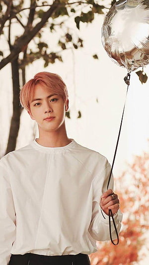 Jin from BTS holding a silver balloon in a white shirt with autumn foliage background HD phone wallpaper