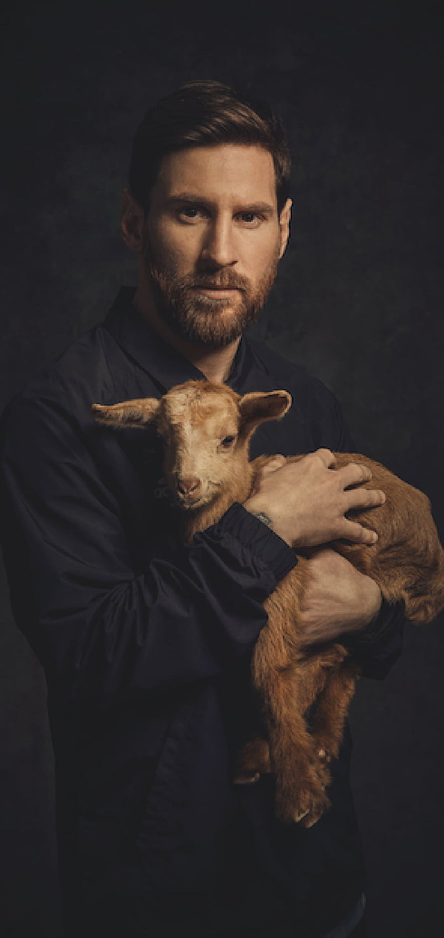 Lionel Messi Holding a Brown Lamb in a Dark Studio Portrait HD phone wallpaper