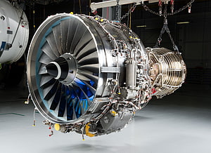 High-Tech Jet Engine Turbine with Blue Fan Blades Suspended in Industrial Hangar HD wallpaper