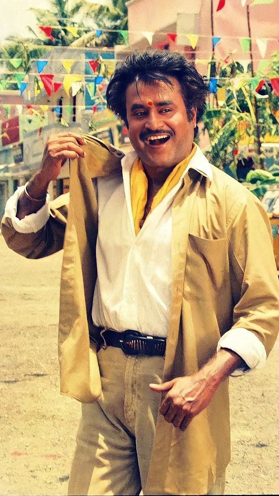 Rajinikanth in festive attire with colorful bunting and a warm smile HD phone wallpaper