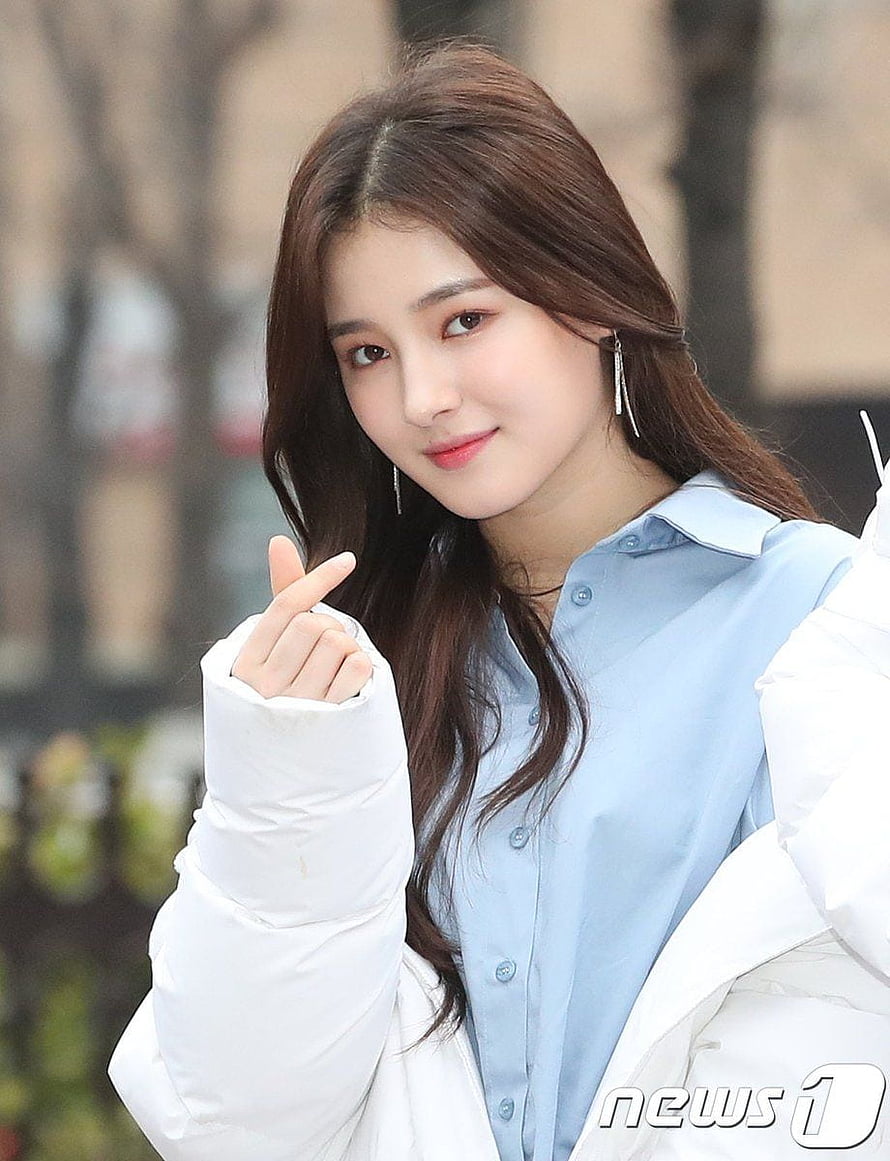 Nancy from Momoland making a finger heart gesture in a blue shirt and white jacket HD phone wallpaper