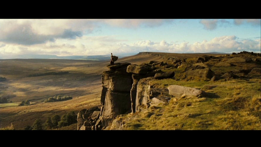 Pride and Prejudice 2005 Film Scene of a Figure Standing on a Rocky Cliff Overlooking Vast Countryside HD wallpaper