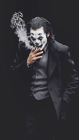 Joker in a dark suit smoking a cigarette with dramatic smoke against a black background HD phone wallpaper