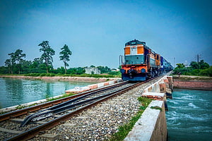 Indian Railways diesel locomotive crossing a river bridge with lush green landscape HD wallpaper