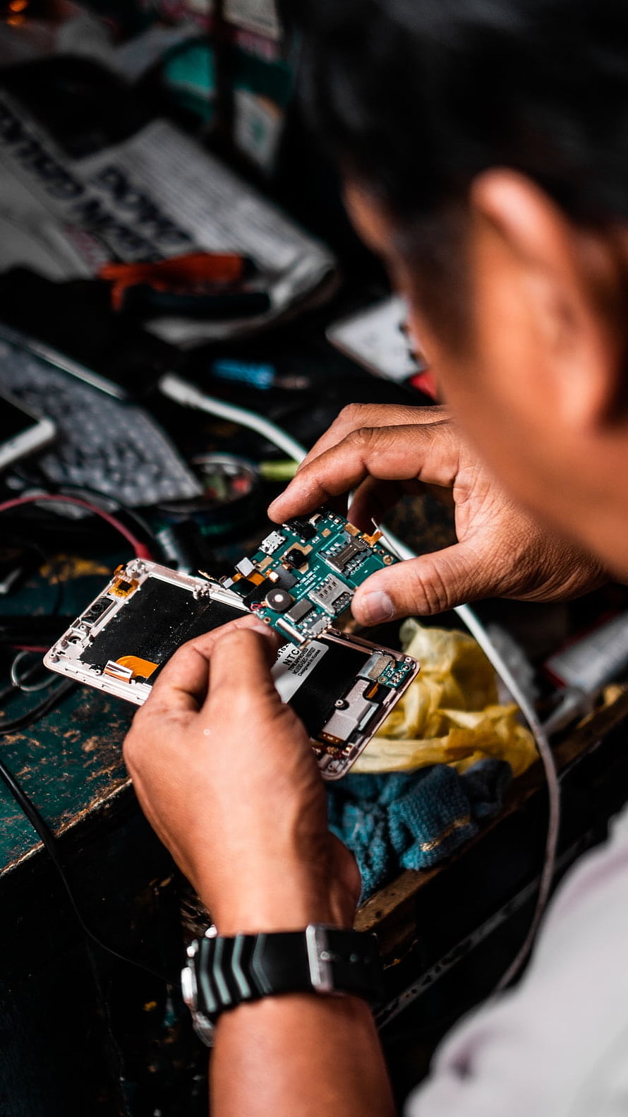 Technician Repairing Smartphone Circuit Board in Workshop HD phone wallpaper