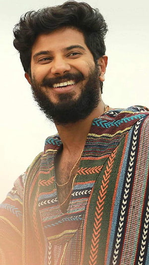 Dulquer Salmaan smiling portrait wearing a colorful patterned traditional kurta with a gold chain HD phone wallpaper
