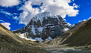 Sacred Mount Kailash Peak Rising Above Rugged Tibetan Valley Under Dramatic Clouds HD wallpaper