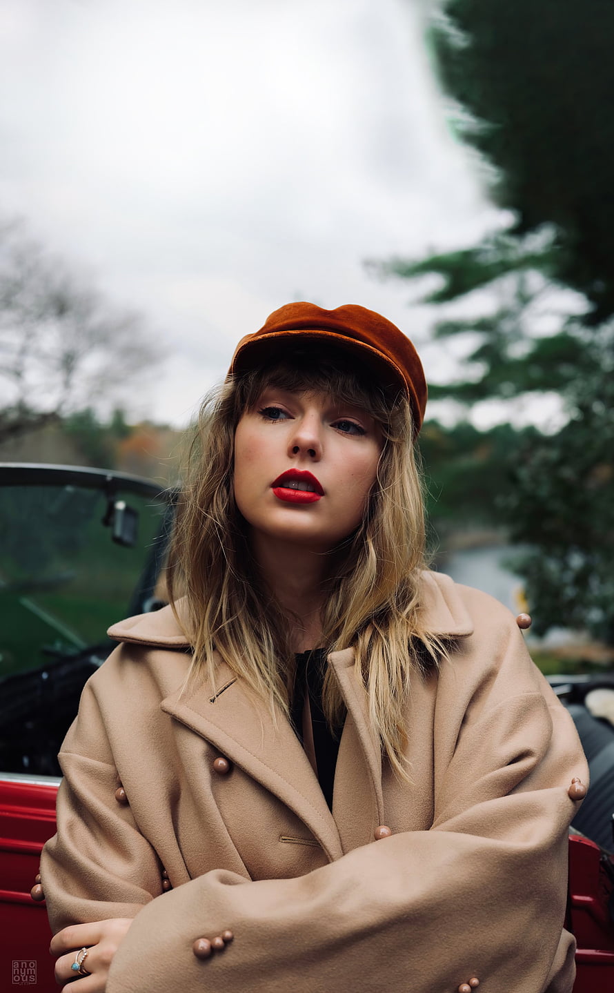 Taylor Swift wearing a beige coat and orange cap sitting in a red car HD phone wallpaper
