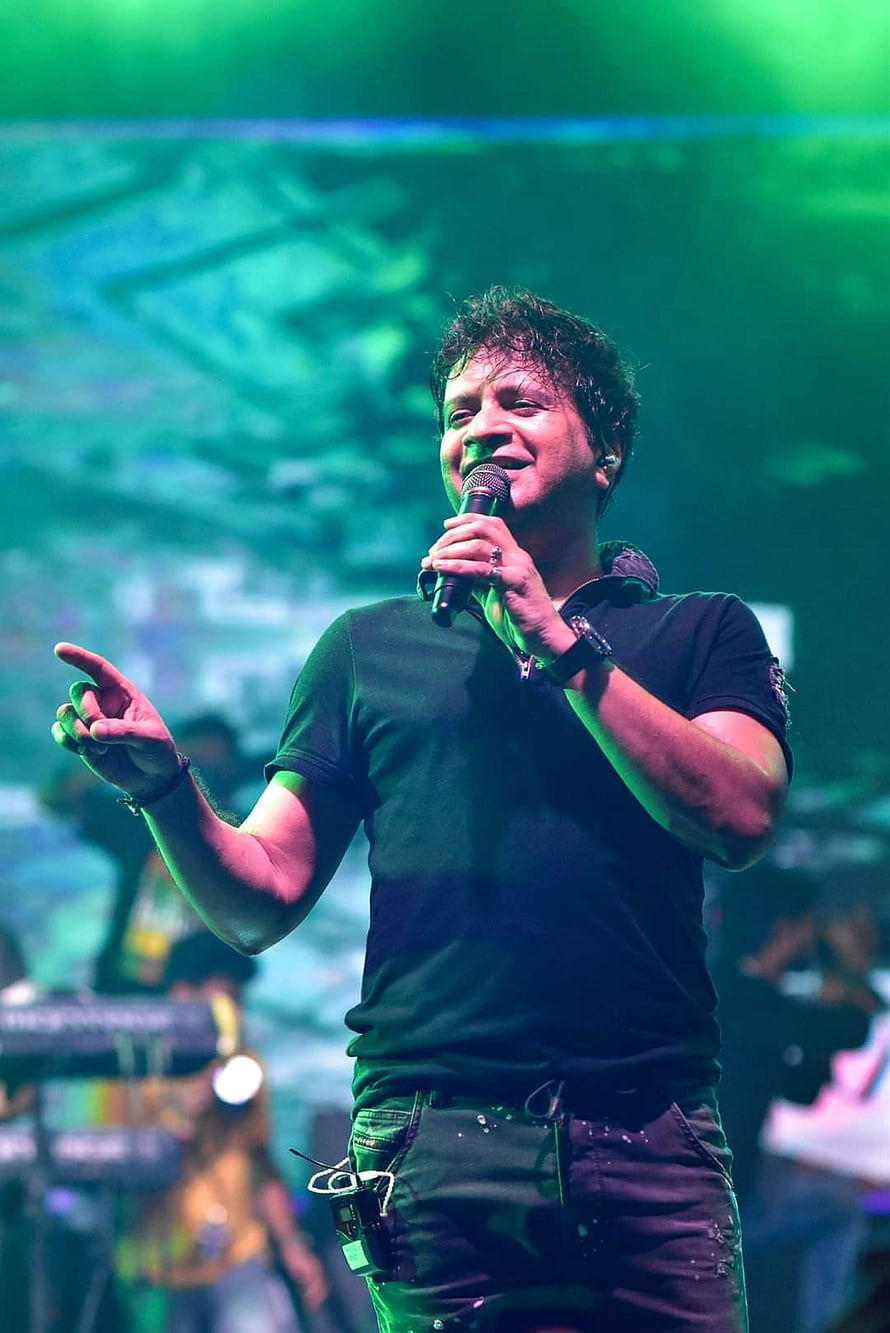 Arijit Singh performing live on stage with a microphone under green concert lighting HD phone wallpaper