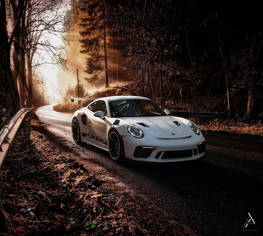 White Porsche 911 GT3 RS driving on a winding forest road with golden sunlight HD wallpaper