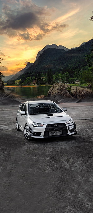Silver Mitsubishi Lancer Evolution X parked on a lakeside road at sunset with mountains in the background HD phone wallpaper