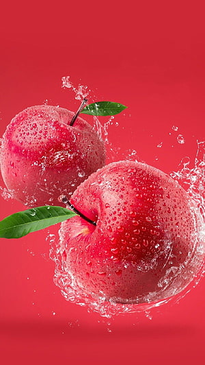 Two Fresh Red Apples with Green Leaves and Water Droplets on a Vibrant Red Background HD phone wallpaper