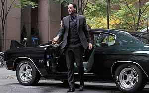 John Wick Stepping Out of a Black Classic Muscle Car in a Dark Suit HD wallpaper