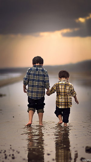 Two Young Boys Walking Hand in Hand on a Wet Beach at Sunset HD phone wallpaper