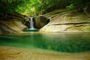 Serene Forest Waterfall Cascading Into a Turquoise Pool Surrounded by Lush Greenery and Smooth Rocks HD wallpaper