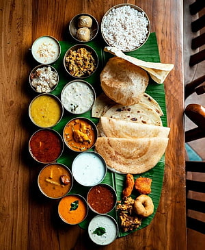 Traditional South Indian Thali with Rice, Dosa, and Multiple Curries on Banana Leaf HD phone wallpaper