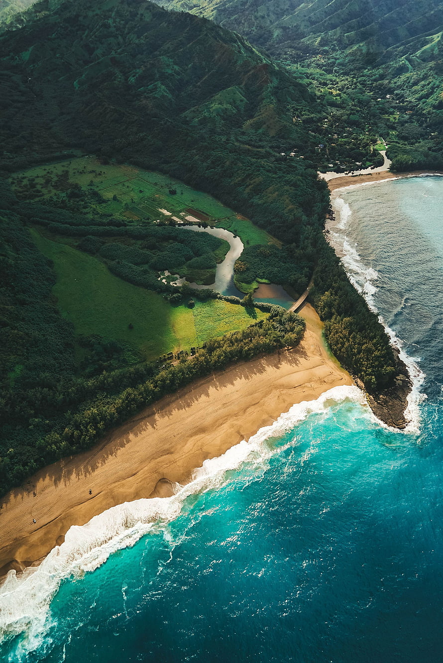 Aerial View of Turquoise Ocean Waves Crashing on Sandy Beach with Lush Green Mountains HD phone wallpaper