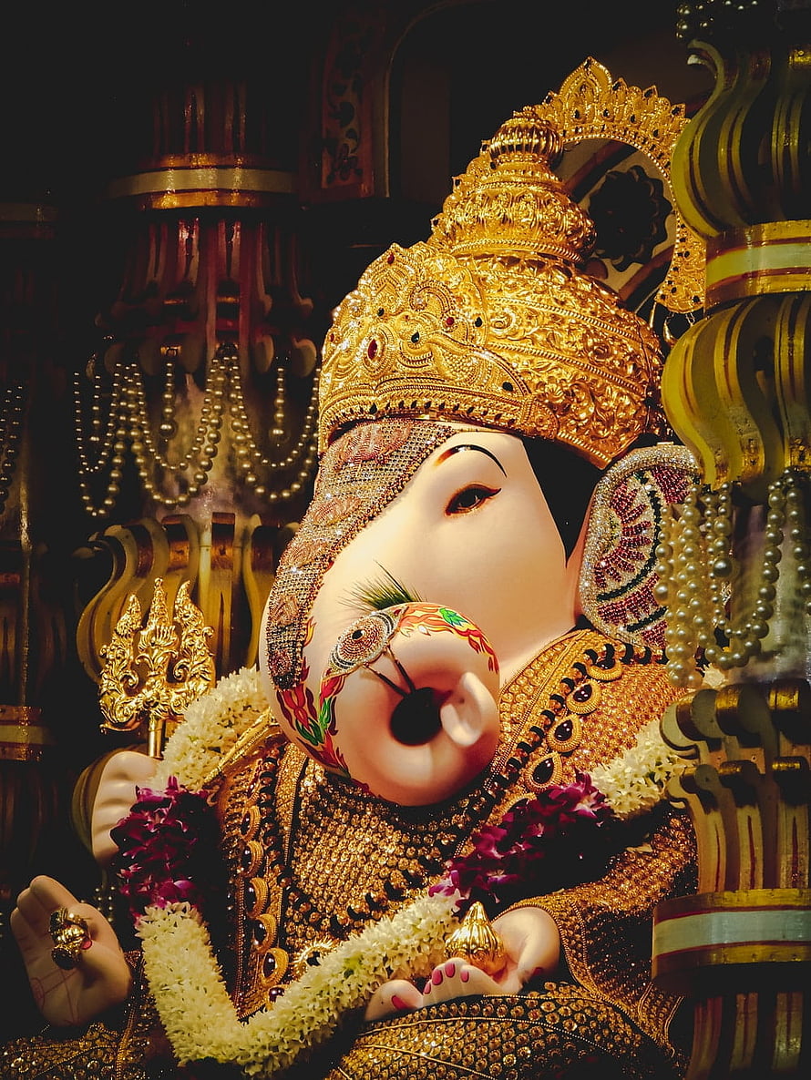Ornate Golden Ganesha Idol With Intricate Crown And Floral Garlands HD phone wallpaper