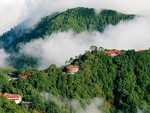 Mussoorie Hill Station with Misty Forested Peaks and Red-Roofed Buildings HD wallpaper