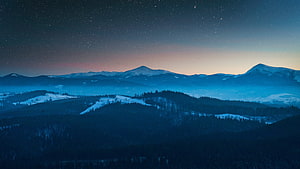 Snow-Capped Mountain Ranges Under a Starry Night Sky with Aurora Glow HD wallpaper