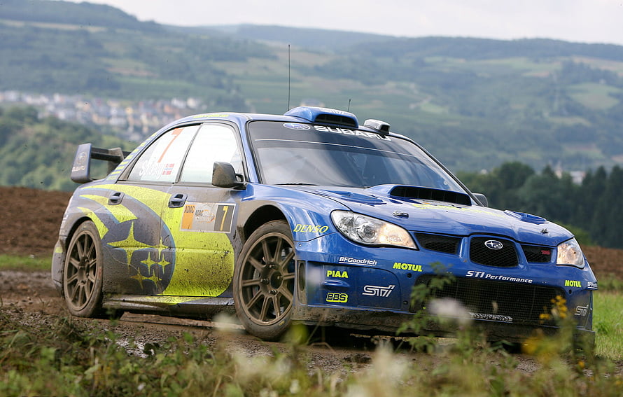 Blue Subaru Impreza WRX STI rally car on a dirt track with sponsor decals HD wallpaper