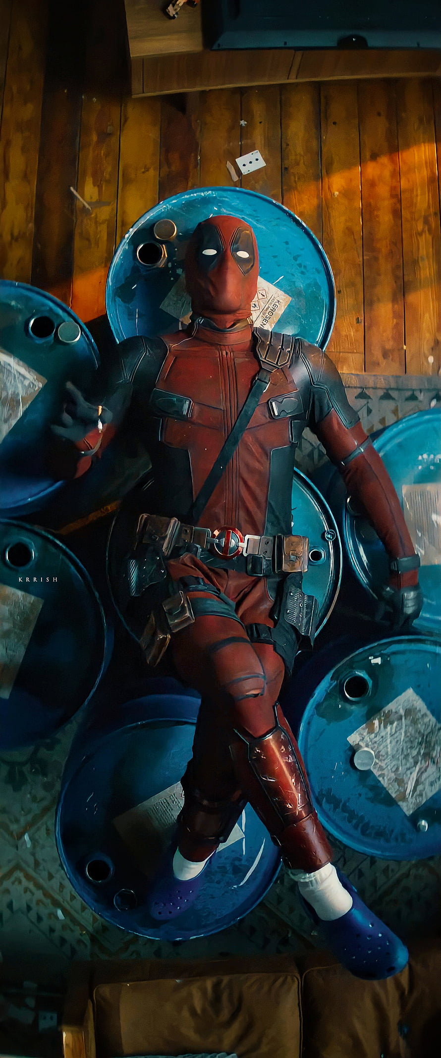 Deadpool in red and black suit lounging on blue barrels with purple clogs HD phone wallpaper