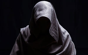 Anonymous figure in a dark hooded cloak against a black background HD wallpaper