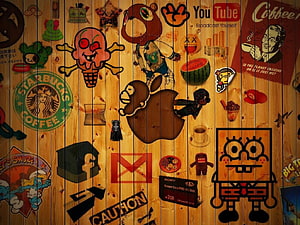 Wooden Wall Covered In Pop Culture Stickers Including SpongeBob, Apple, Starbucks, And YouTube Logos HD wallpaper