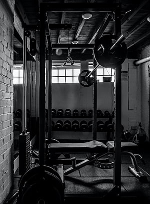 Moody Black and White Photo of a Rustic Home Gym with Power Rack and Dumbbells HD phone wallpaper