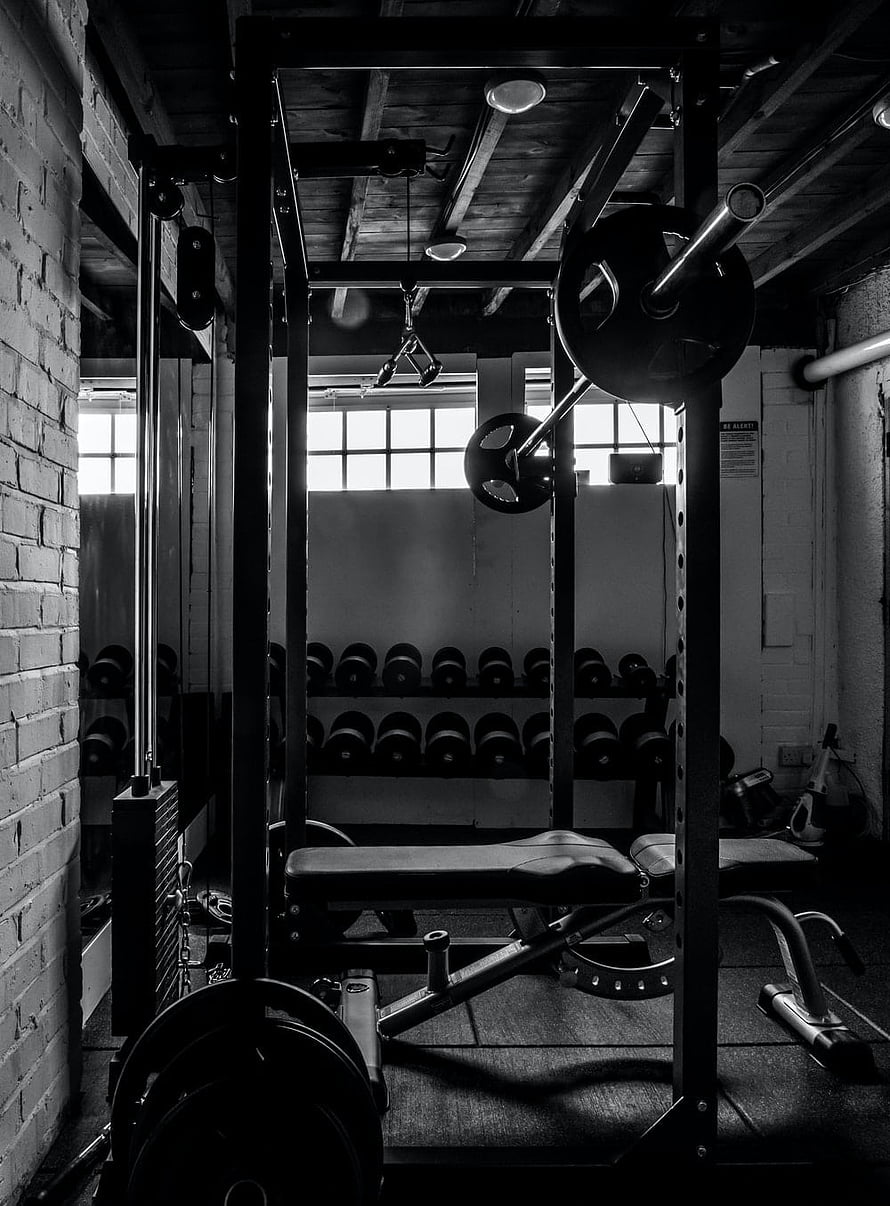 Moody Black and White Photo of a Rustic Home Gym with Power Rack and Dumbbells HD phone wallpaper