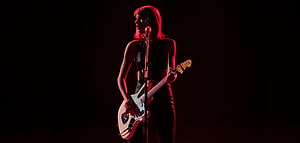 Taylor Swift performing live on stage with electric guitar under dramatic red lighting HD wallpaper