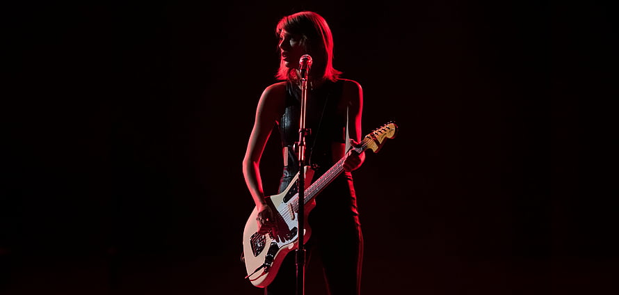 Taylor Swift performing live on stage with electric guitar under dramatic red lighting HD wallpaper