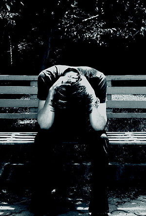 Black and white photo of a person sitting on a bench holding their head in despair HD phone wallpaper