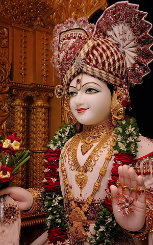 Lord Jagannath adorned with intricate golden jewelry and a red and white turban, holding flowers in a divine pose HD phone wallpaper
