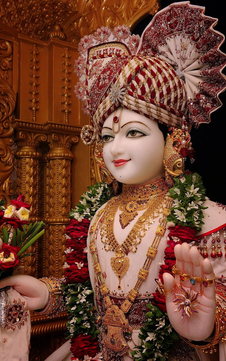 Lord Jagannath adorned with intricate golden jewelry and a red and white turban, holding flowers in a divine pose HD phone wallpaper