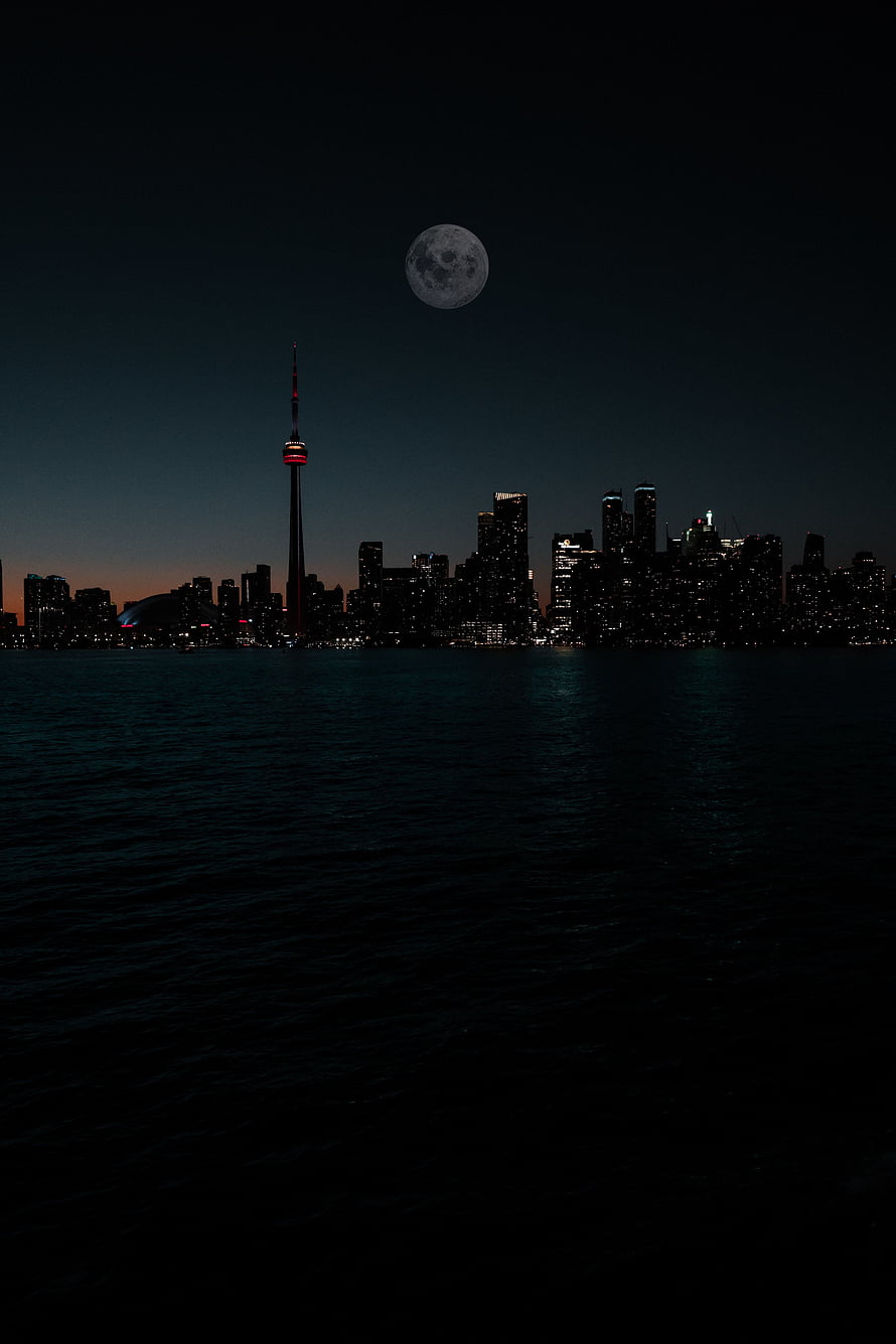 Toronto skyline at night with the full moon rising over Lake Ontario and the CN Tower HD phone wallpaper