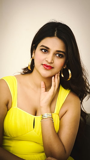 Niddhi Agarwal in a bright yellow dress with gold hoop earrings and red lipstick HD phone wallpaper