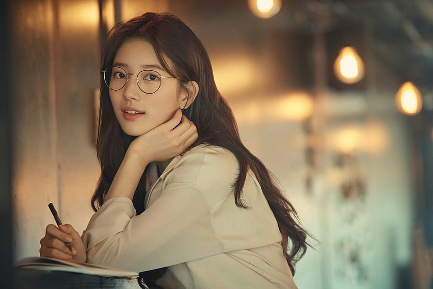 Bae Suzy Portrait in Warm Cafe Setting with Round Glasses and Notebook HD wallpaper