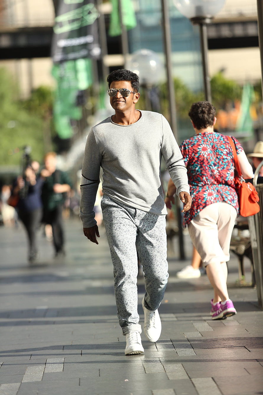 Puneeth Rajkumar in Grey Sweatshirt and Patterned Trousers Walking on a City Street HD phone wallpaper