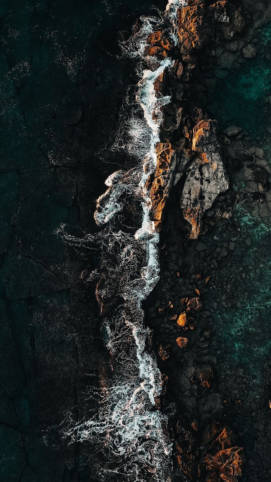 Aerial View of Dark Rocky Coastline with White Sea Foam and Turquoise Water HD phone wallpaper