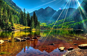 Serene Mountain Lake with Sun Rays and Pine Forest Reflection HD wallpaper