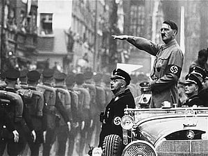 Historical black and white photograph of Adolf Hitler giving a Nazi salute from an open car during a military parade HD wallpaper