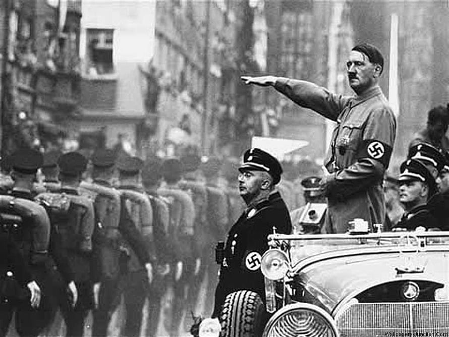 Historical black and white photograph of Adolf Hitler giving a Nazi salute from an open car during a military parade HD wallpaper