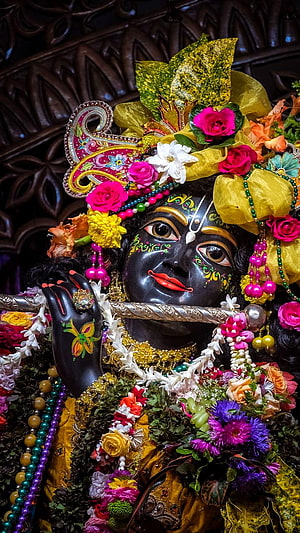 Colorful Lord Krishna Statue Playing Flute With Floral Crown And Peacock Feather HD phone wallpaper