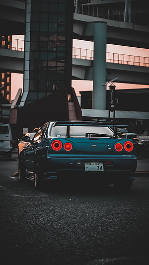 Rear View of Blue Nissan Skyline GT-R R34 in Urban Setting at Sunset HD phone wallpaper