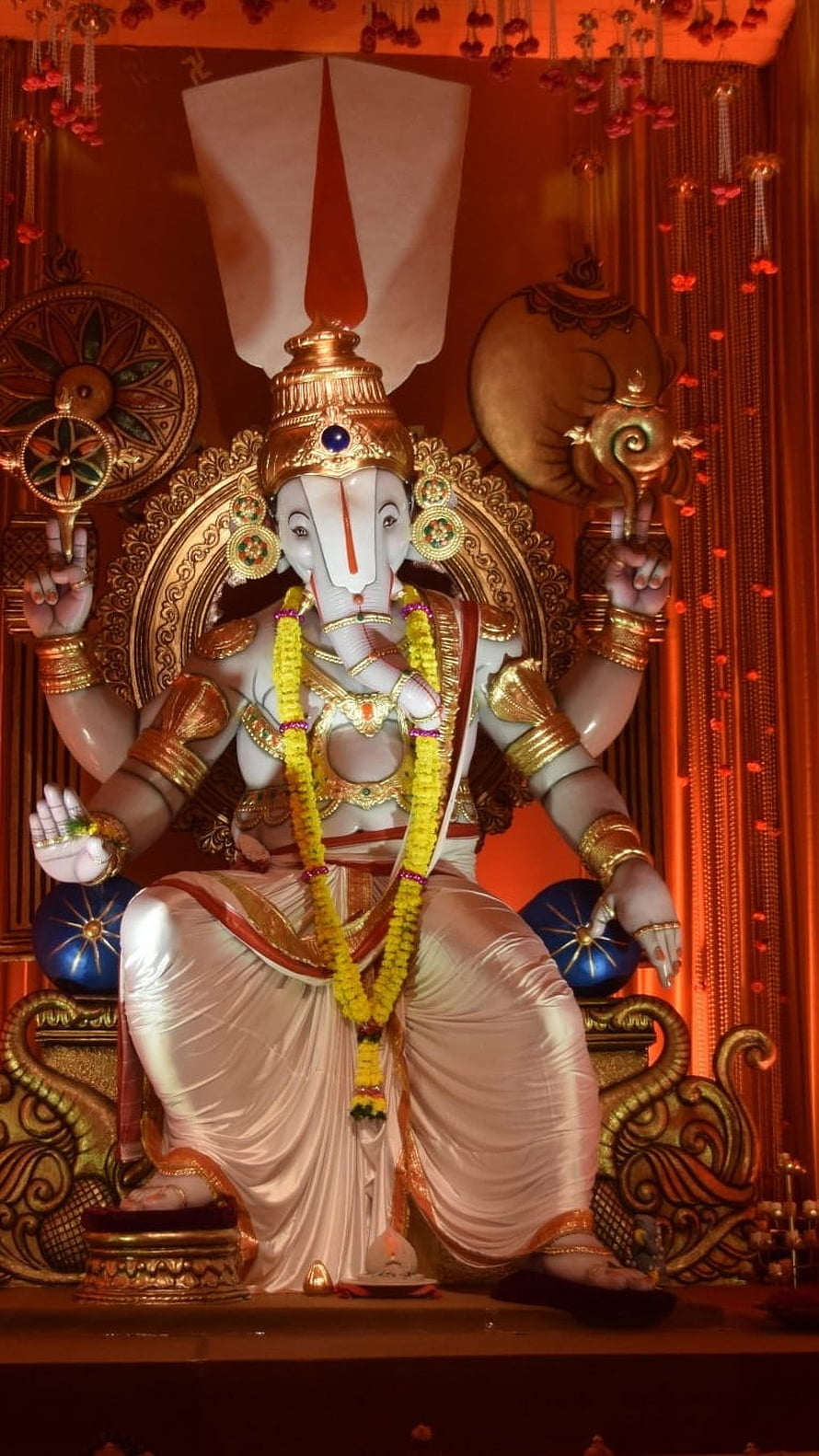 Lord Ganesha Temple Idol Adorned With Marigold Garland And Golden Ornaments HD phone wallpaper