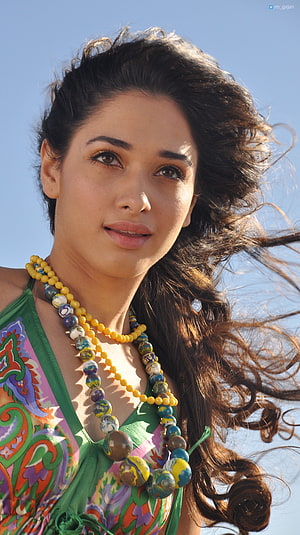 Tamanna Bhatia in a colorful paisley top with layered beaded necklaces against a clear blue sky HD phone wallpaper