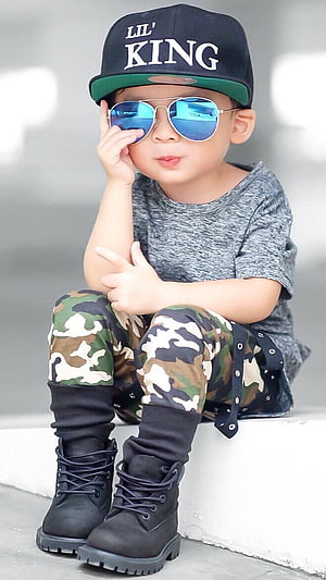 Stylish Toddler Boy in Camouflage Pants, Black Boots, and Aviator Sunglasses HD phone wallpaper