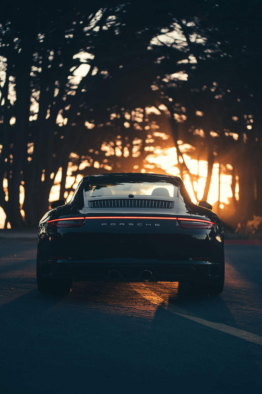 Rear View of a Black Porsche 911 on a Forest Road at Golden Hour HD phone wallpaper