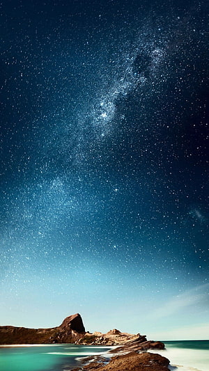 Milky Way Galaxy Arching Over Turquoise Coastal Waters and Rocky Shoreline HD phone wallpaper